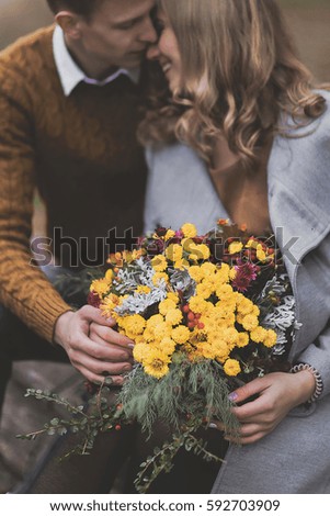Flower bouquet on background of coupleâ??s smiling love, affection. Boy and girl of European appearance with warm clothes, pictures with soft background bokeh blur fall. Concept of happiness, joy