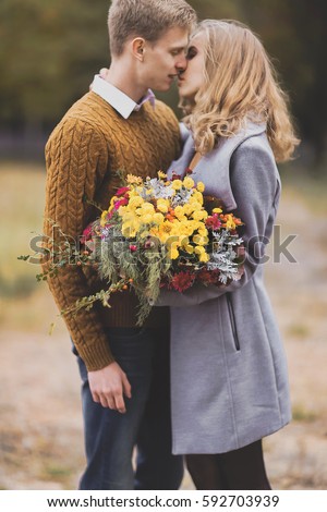 Young girl and guy with blond hair hug, show love, affection. Boy and girl of European appearance with warm clothes, pictures with soft background bokeh blur fall. Concept of happiness, joy, endless
