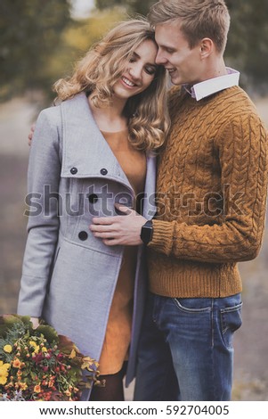 Young girl and guy with blond hair smiling hug, show love, affection. Boy with smart watch and girl of European appearance with warm clothes, pictures with soft background bokeh blur fall. Concept of