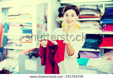 Young woman checking quality of fabric for dress at drapery shop