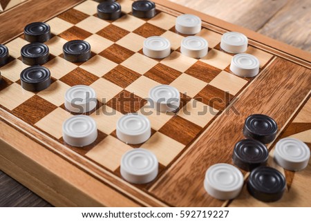 checker board with checkers on wooden background .