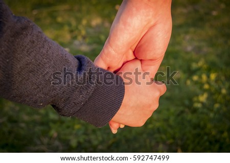 Little child holding hand of his mother stock image. Parent and child, parenthood illustrative image.