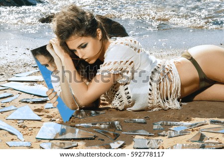 Beautiful woman on the beach with a shards of mirror