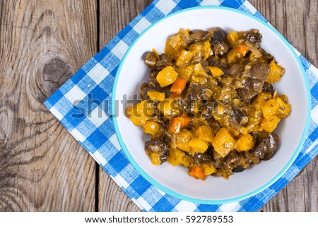 Vegetable stew with pumpkin and mushrooms on wooden background. View from the top. Studio Photo