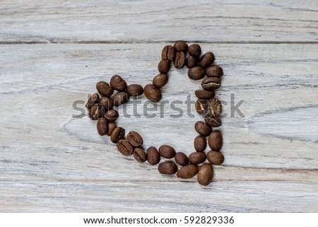Roasted coffee beans in a shape of a heart on wooden background.