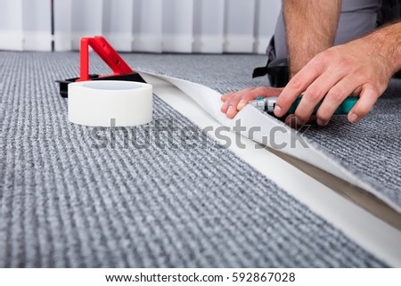 Close-up Of Person's Hand Lying Carpet Using Carpenter Tools Royalty-Free Stock Photo #592867028