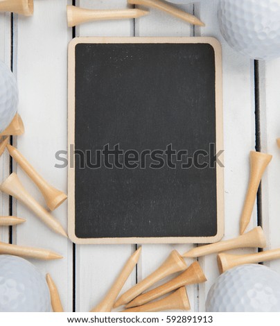 Used golf balls and tee with mini blank blackboards over wooden background