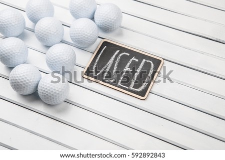 Golf balls with 'USED' text on mini blackboard over wooden background