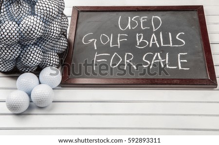 Used golf balls and blackboard with text over wooden background