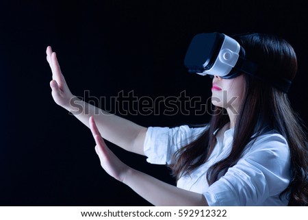 Asian Chinese young woman using vitual reality smart glasses in vitual space.low key photo