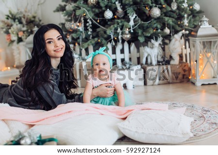 Baby girl and mother near Christmas tree