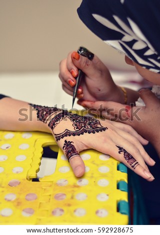 Artist applying henna tattoo on women hand 