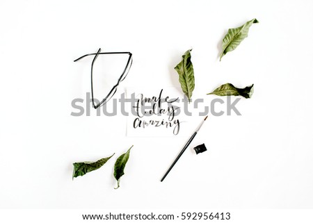Inspirational quote "Make Today Amazing" written in calligraphic style on paper with green leaf and glasses on white background. Flat lay, top view.