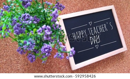 flower and Chalk board with text HAPPY TEACHER'S DAY on a wooden table.

