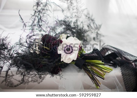 Stylish black bouquet tied with a black ribbon on a white cloth at the window