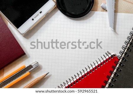 empty paper surround with pencil, notebook, cutter, stationery on wood background