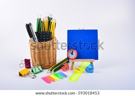 School supplies - pen, pencil, ruler, clip, sharpener, blue board and calculator in rattan basket isolated on white