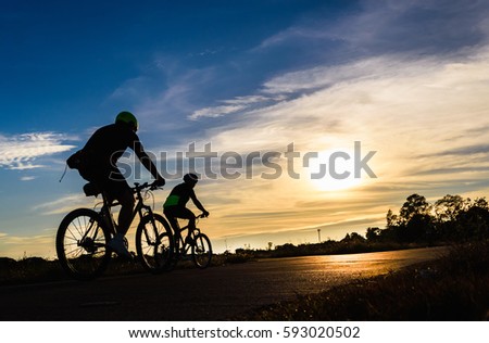 Men ride bicycle at sunset,Silhouette background.