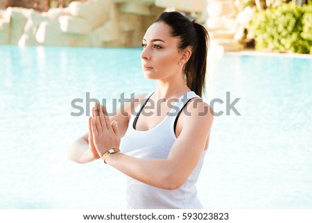 Image of attractive young fitness lady make yoga exercises outdoors near pool.