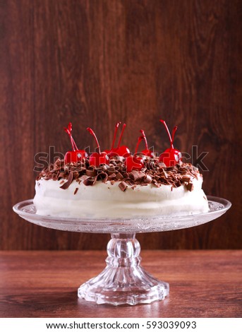 Cherry and chocolate cake on plate over wooden background