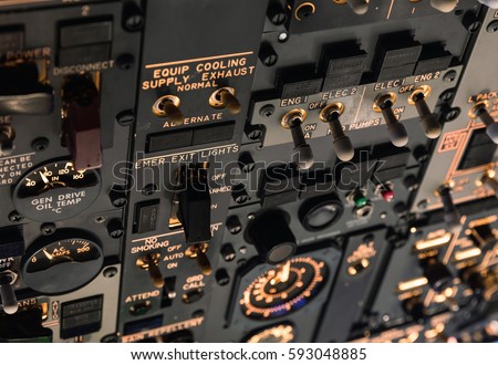 Detailed view of the upper set of switches in a large airliner. Selective focus. Low Light from a plane control cockpit in the dark vintage, detail on the interior cockpit Royalty-Free Stock Photo #593048885