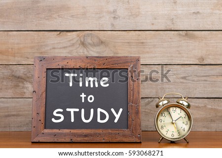 Alarm clock and blackboard with text "Time to study"" on brown wooden background Royalty-Free Stock Photo #593068271