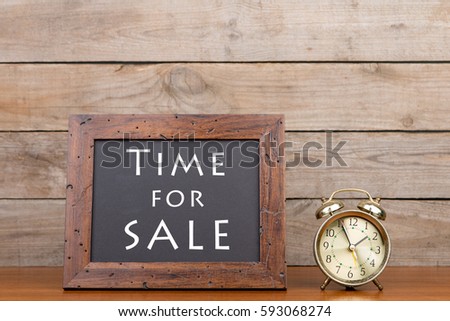 Alarm clock and blackboard with text "Time for sale"" on brown wooden background