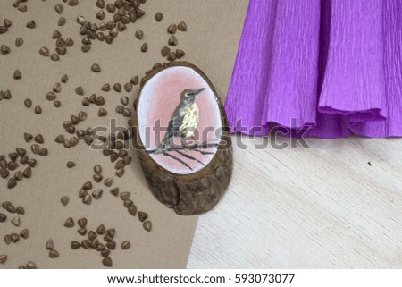 Wooden stump. Beautiful picture bird painted on a wooden stump. Paper pink substrate. Buckwheat groats