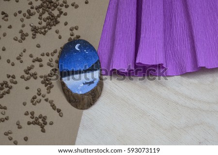 Wooden stump. Beautiful picture blue sky landscape painted on a wooden stump. Paper pink substrate. Buckwheat groats