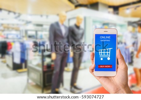 Woman hand holding smartphone against blur bokeh of shop background with word online shopping buy now
