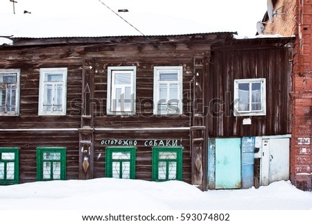 Written sign "Warning. Dogs" on the wall of a wooden house in countryside in snowy winter in Russia
