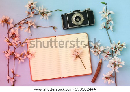 top view image of spring white cherry blossoms tree, open blank notebook, old camera on wooden table