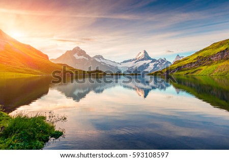 Colorful summer sunrise on Bachalpsee lake with Schreckhorn and Wetterhorn peaks on background. Picturesque morning scene in the Swiss Bernese Alps, Switzerland, Europe. 