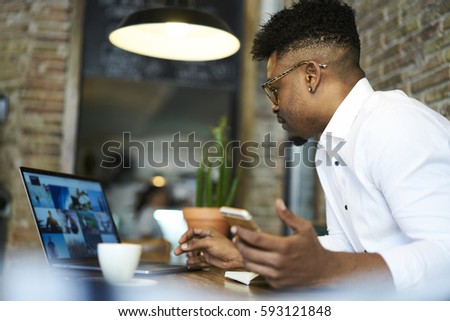 Confident male journalist watching broadcasting video from official event while thinking over  creation article for popular political online issue using laptop computer with mock up screen and wifi