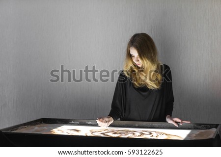 The woman draws on sand, sand animation, sand is pouring from his hands