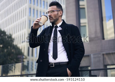 Confident well-dressed male owner of trading corporation drinking coffee outdoors during lunch break resting after important parleys with investors signed contracts with media marketing agency 
