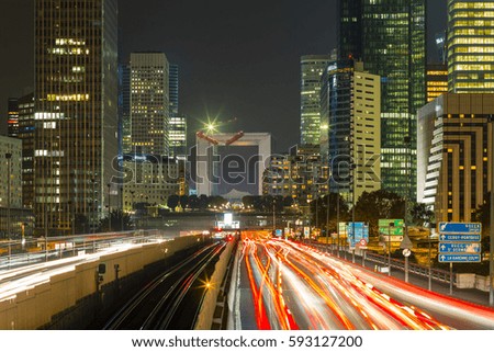 Paris cityscape with modern buildings in business district La Defense with dynamic street traffic and car lights by night. Glass facade skyscrapers. Concept of economics, finances. Copy space. Toned