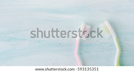 Two pastel toothbrushes with pink flowers mint herb over green textured background. Spring colors. Personal dental health care hygiene. Healthy couple concept