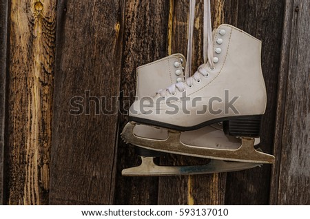 White skate hanging on the angle in front of wooden background. Toning. Vintage 
