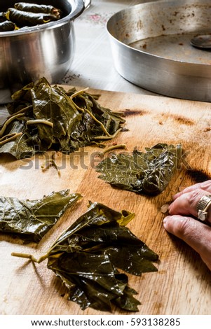 Woman is wrapping grape leaves for turkish dolma with minced meat.
