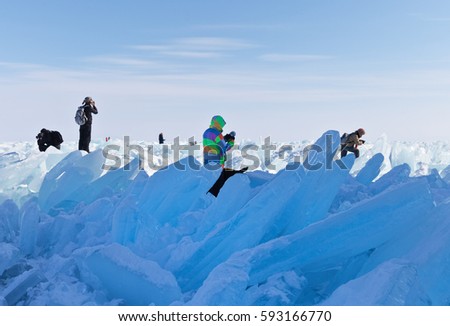 Lake Baikal in winter. Unidentified tourists taking pictures of ice hummocks