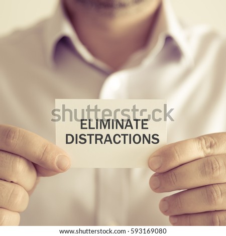 Closeup on businessman holding a card with text ELIMINATE DISTRACTIONS, business concept image with soft focus background and vintage tone