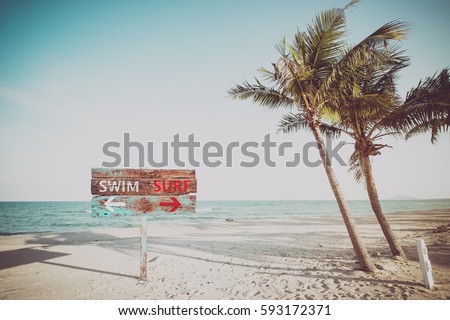 Old wood sign navigate swimming and surfing on a tropical beach in the summer. Vintage color filter effects. Royalty-Free Stock Photo #593172371