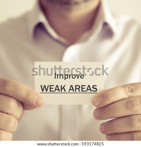Closeup on businessman holding a card with text IMPROVE WEAK AREAS, business concept image with soft focus background and vintage tone