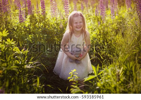 Beautiful little girl smiling and playing with a basket in his hands in a field of purple flowers