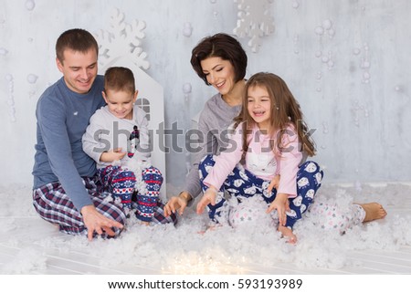 Beautiful family (mom, dad, son and daughter) played indoors with props snow on background Toy houses.