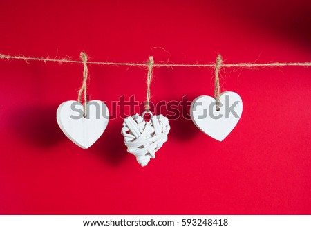 Valentine's Day concept. White wooden hearts hanging on cord on red background