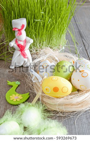 Easter eggs of different colors lying on the table next to the green of fresh grass and the white rabbit