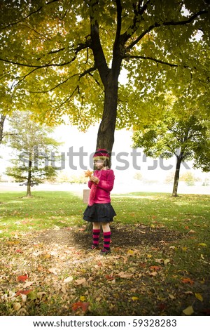 Five year old girl standing under an autumn tree
