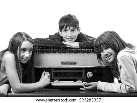 Teenage boys and girls listening to old vintage radio isolated on white in black and white.